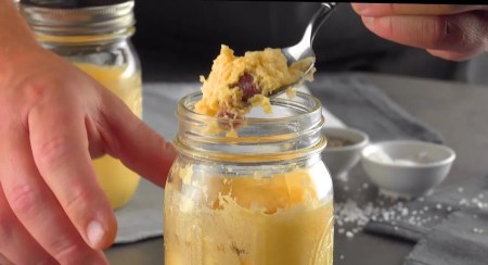 Rührei im Glas, aus dem ein Löffel entnommen wird.