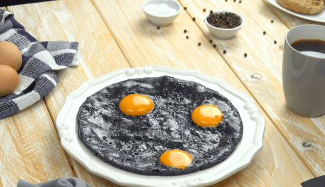 Ein tellergroßes, schwarzes Spiegelei mit 3 Eigelben.