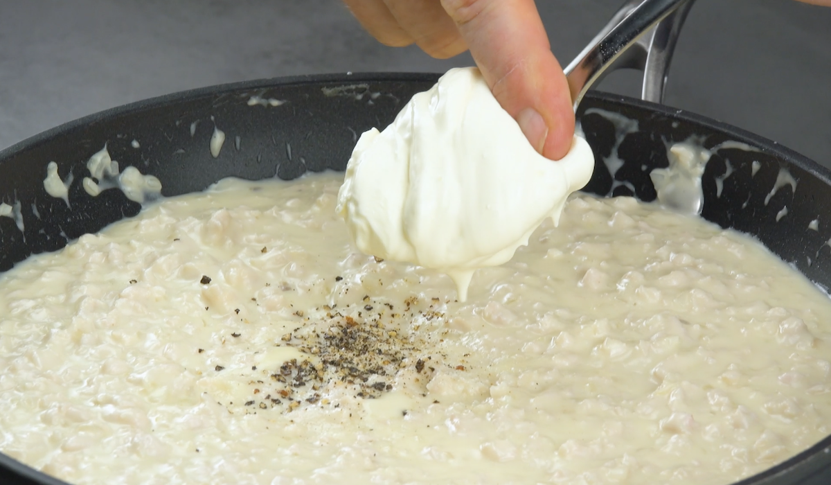 Gehacktes Hühnerfleisch wird in Pfanne gegeben und mit einem Löffel Crème fraîche verfeinert