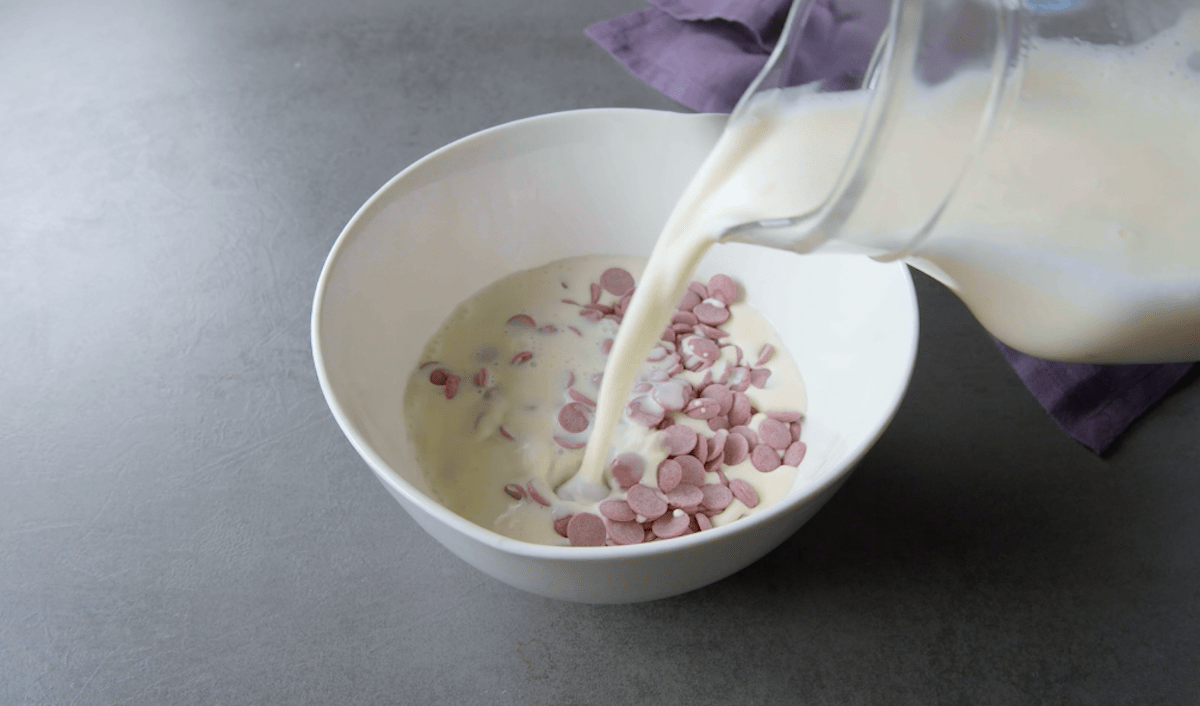 Warme Sahne wird über Ruby-Schokolade gegeben