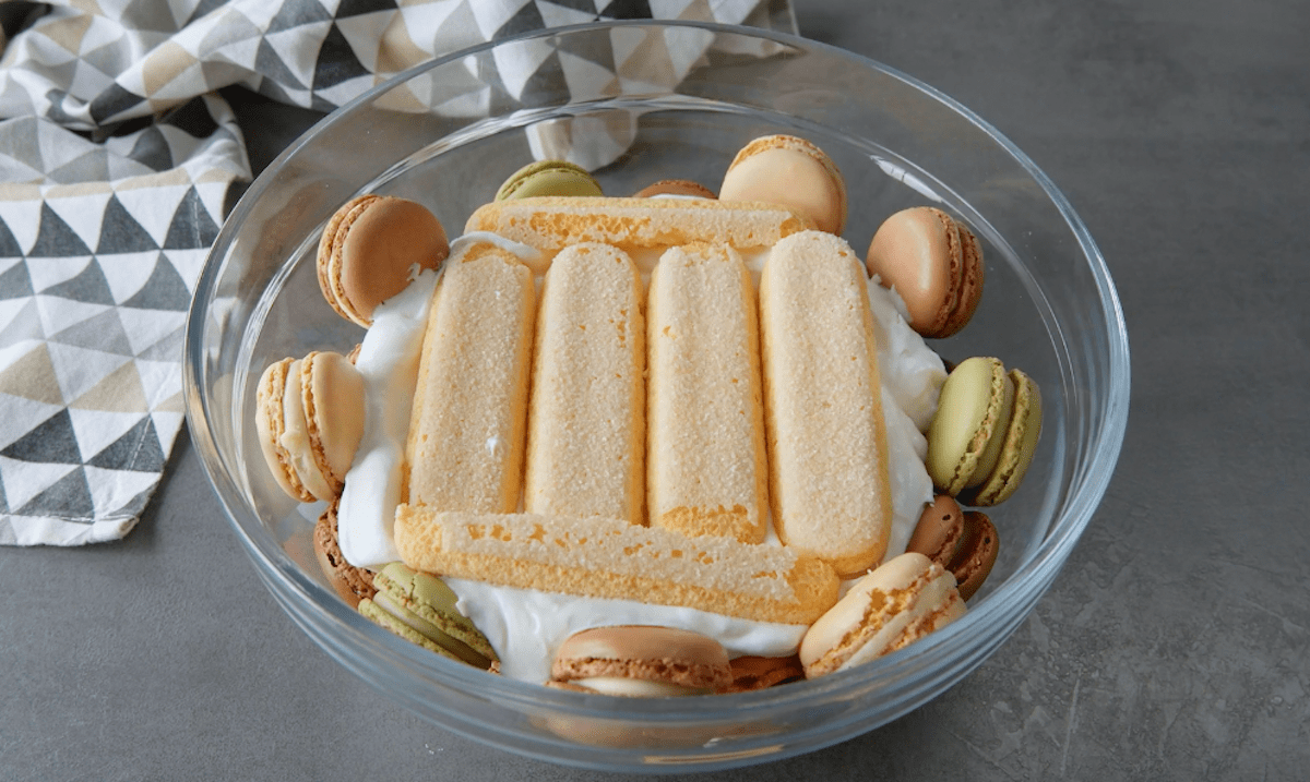 Eine Schüssel mit Macarons, Sahne und Löffelbiskuits