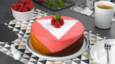 Schiefer Himbeerkuchen in geometrischem Design mit drei Farben, mit Himbeeren und Puderzucker sowie Minze dekoriert.