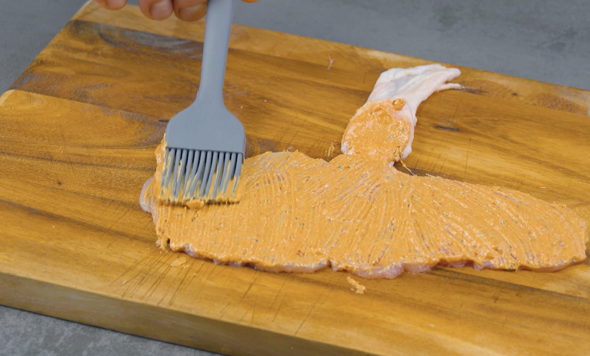 Hähnchenfleisch wird mit Marinade bepinselt