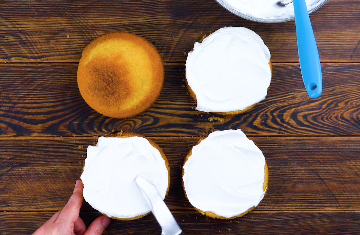 Die Kuchenböden werden mit weißer Frischkäsecreme bestrichen