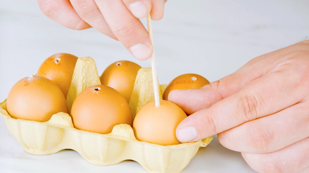 Jemand sticht mit einem Holzstab LÃ¶cher in Eier