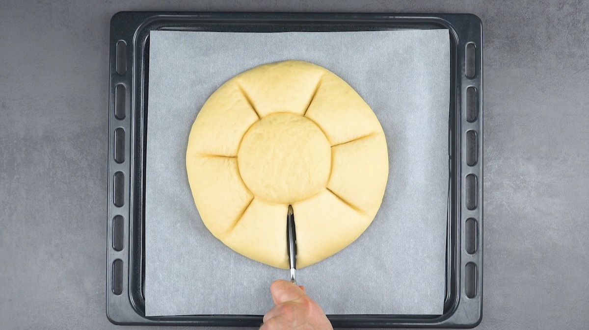 Teigfladen wird mit Messergriff in sieben gleich große Abschnitte unterteilt