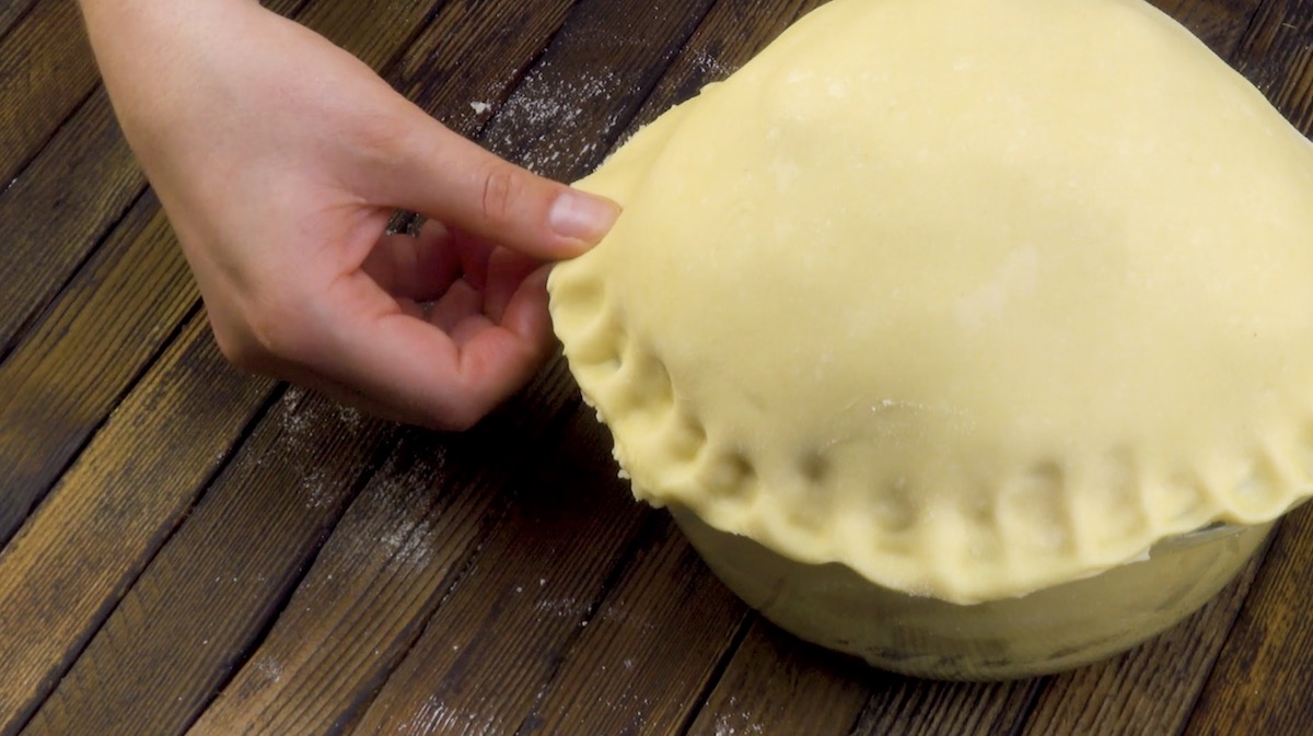 Eine Hand drückt ein Muster in den Teig