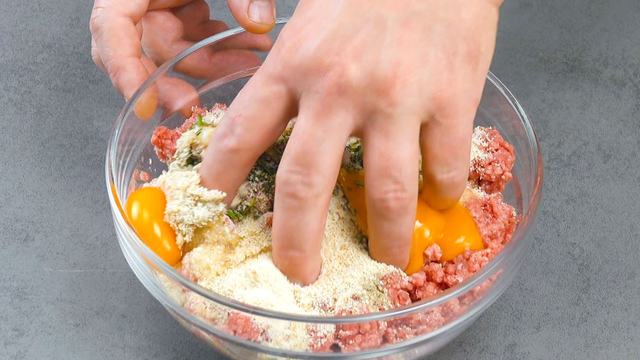 Hackfleisch und restliche Zutaten werden mit Hand in Schüssel verknetet