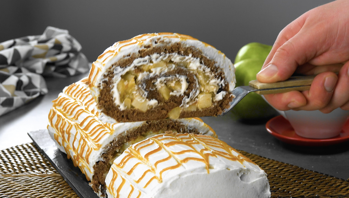 Ein Stück Apfel-Biskuitrolle wird mit Tortenheber aus Roller gehoben