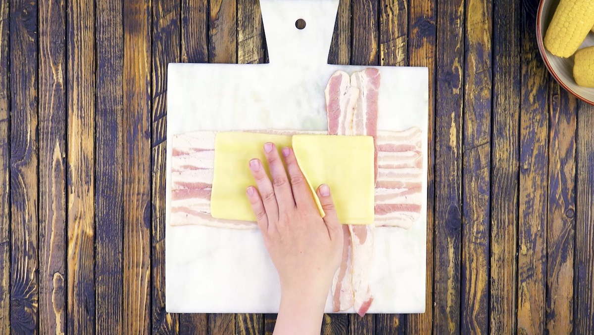 Auch kreuzförmig ausgelegte Baconstreifen werden Käsescheiben gelegt