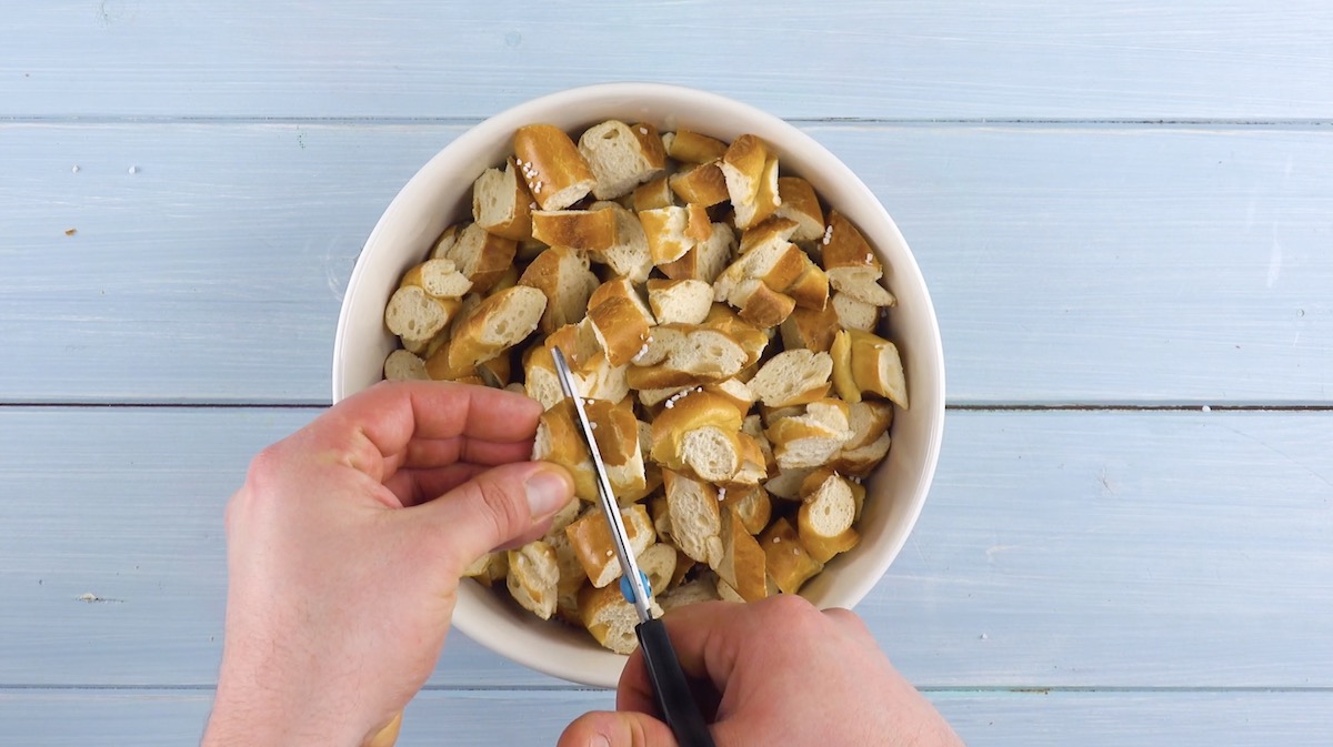 Brezeln werden mit Schere in Schüssel klein geschnitten