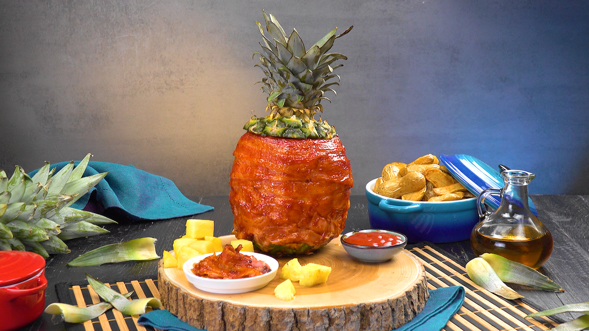 Grillananas, mit HÃ¤hnchenbrust gefÃ¼llt und mit Bacon umwickelt, neben Beilagen und Dip