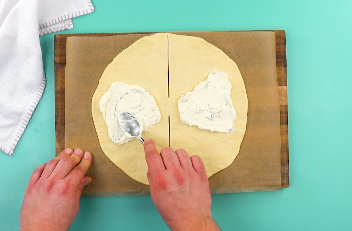 Mit Dill und Pfeffer vermengter Frischkäse wird auf beiden Hälften des Pizzateigs verteilt.