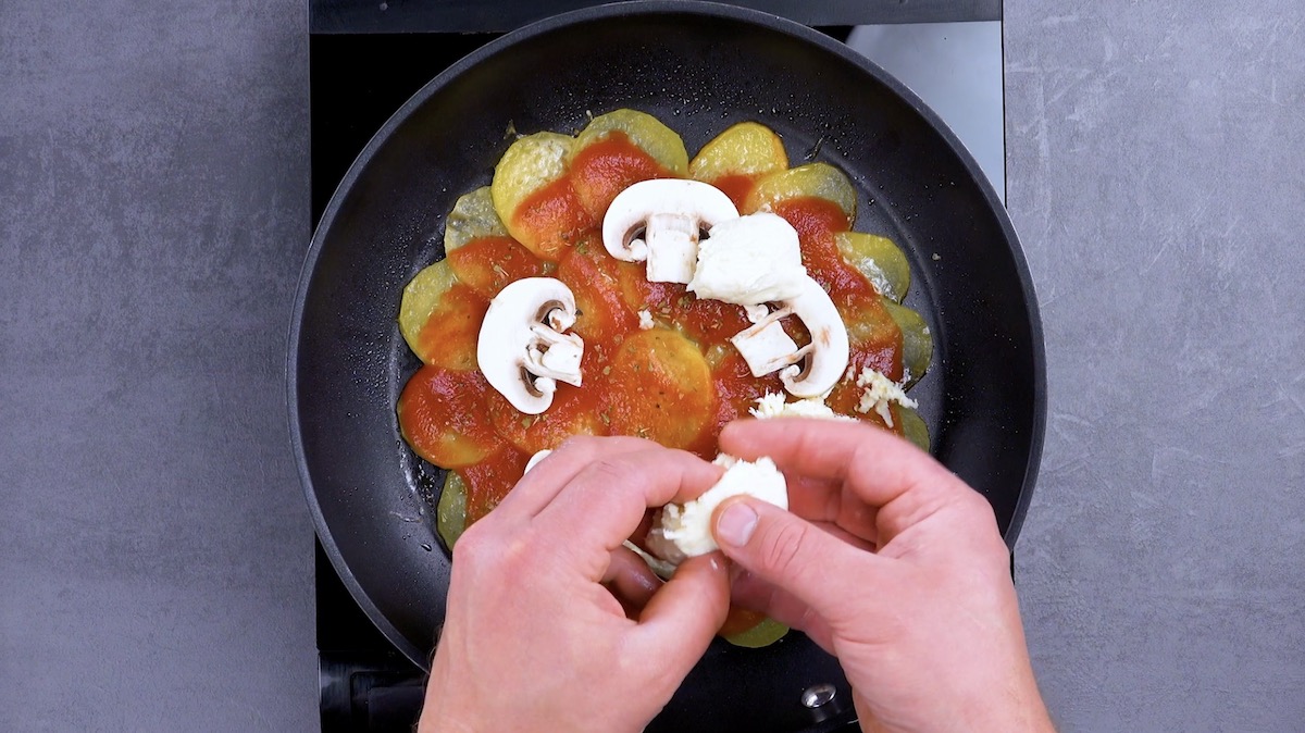 MozzarellastÃ¼cke werden auf Pizza mit Kartoffeln in Pfanne platziert