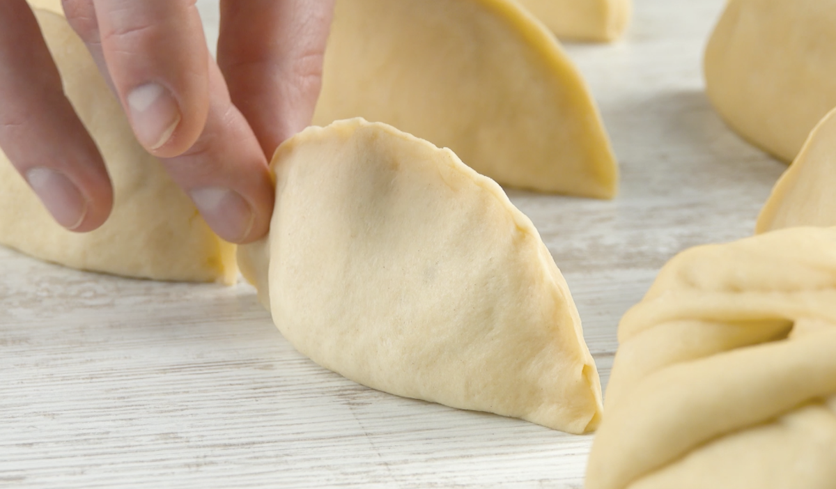 Apfelspalte wird in Teig gehüllt, der rundherum zusammengedrückt wrd