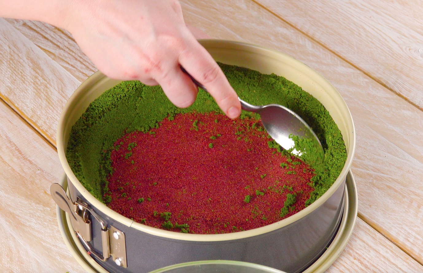 Rand einer Kuchenform wird mit grünen Kekskrümeln ausgekleidet