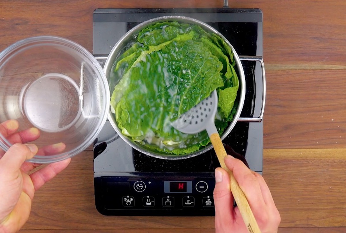 Wirsingblätter werden in einem Topf blanchiert