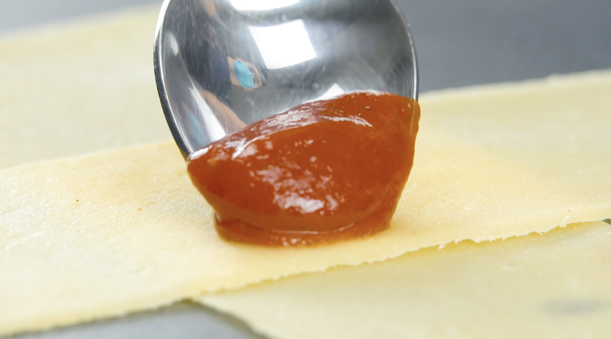 Ein Klecks Chili-Knoblauch-Soße wird auf in die Mitte von Teig-Streifen gegeben