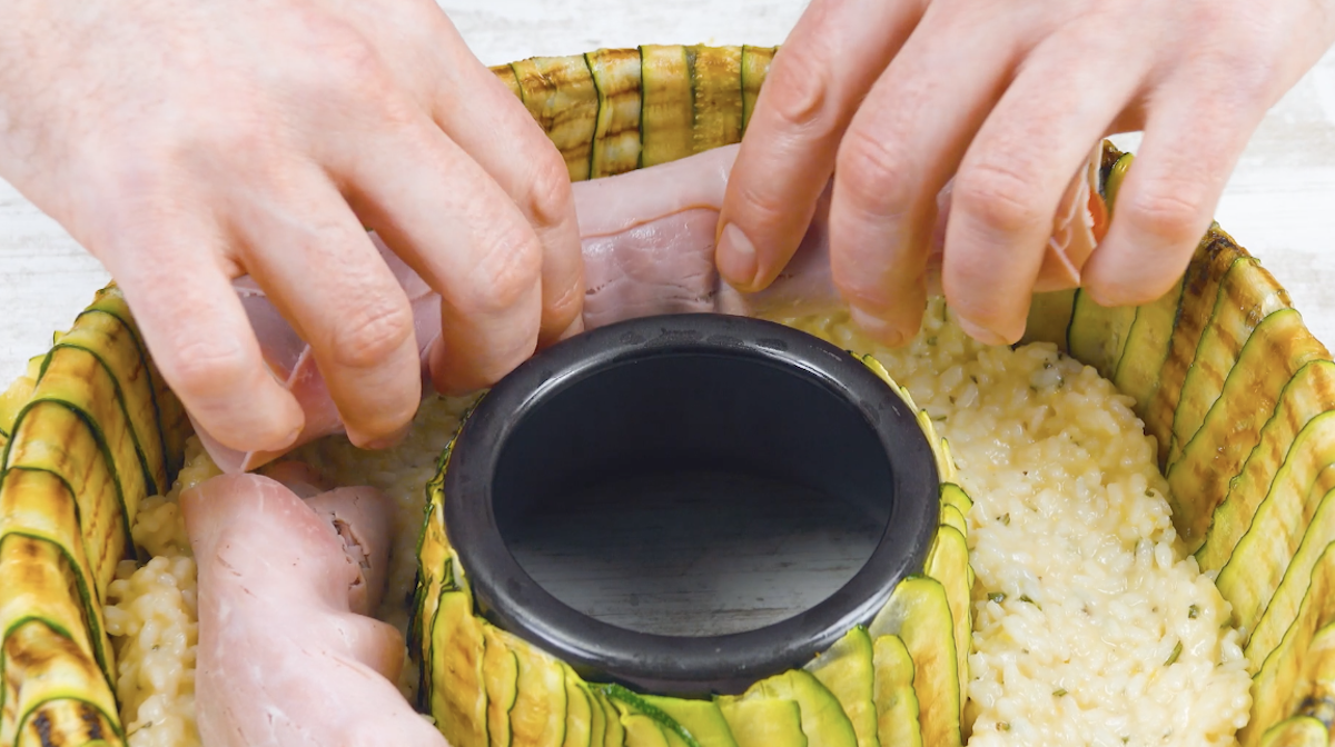 Gefüllte Schinkenröllchen werden auf Risotto in Kuchenform gelegt