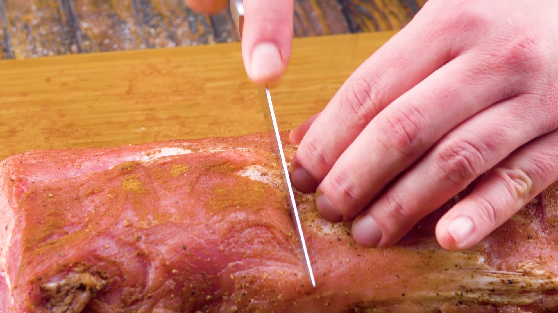 SchweinerÃ¼cken wird mit einem Messer eingeschnitten.