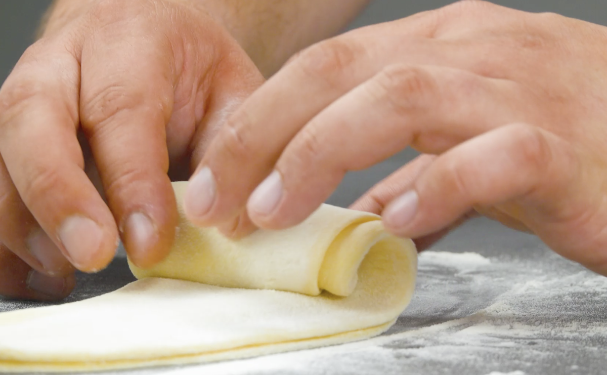 Teig wird zu Röllchen aufgerollt