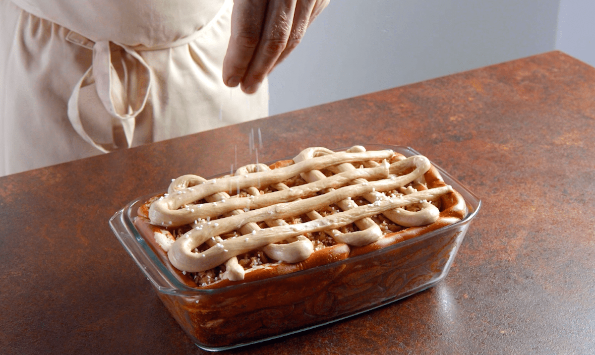 Auf mehrere Schichten Brezeln, Kartoffelpüree, Sauerkraut und Nürnberger Würstchen wird ein Gitter aus Teig gelegt