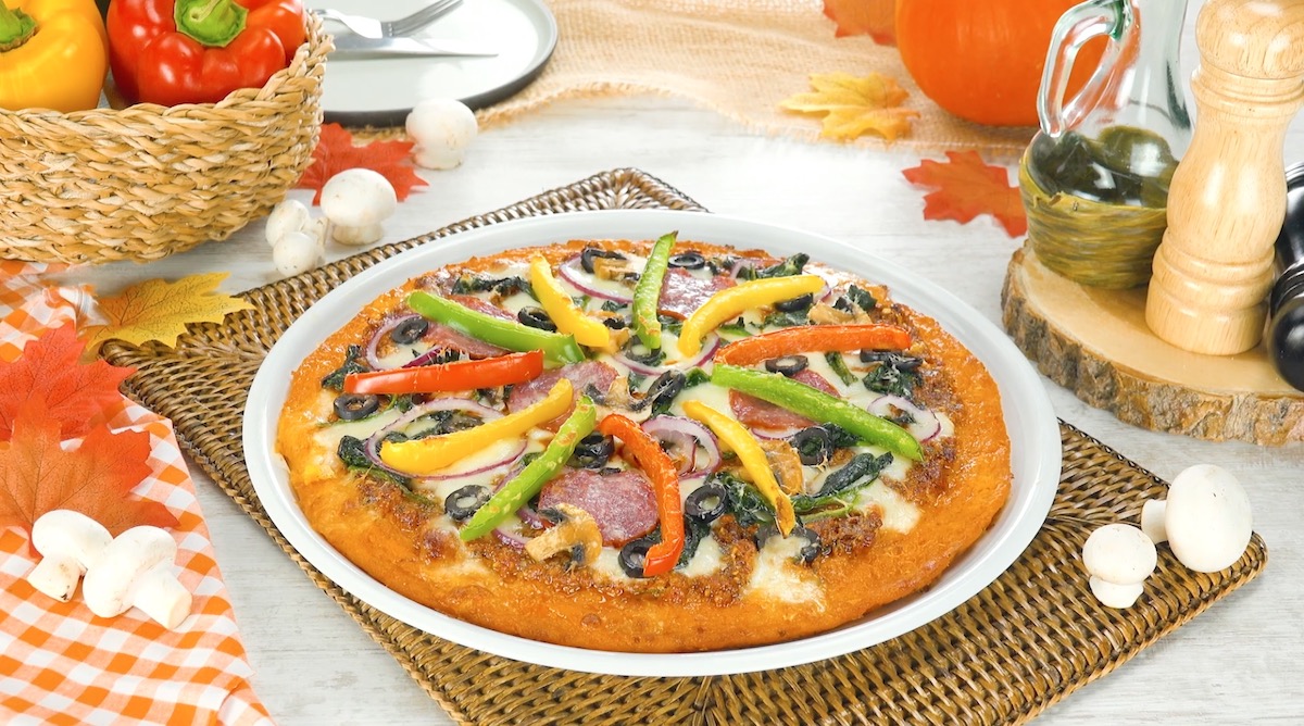 Kürbis-Pizza aus Butternutkürbis mit Paprikastreifen, Spinat und Salami auf einem Teller