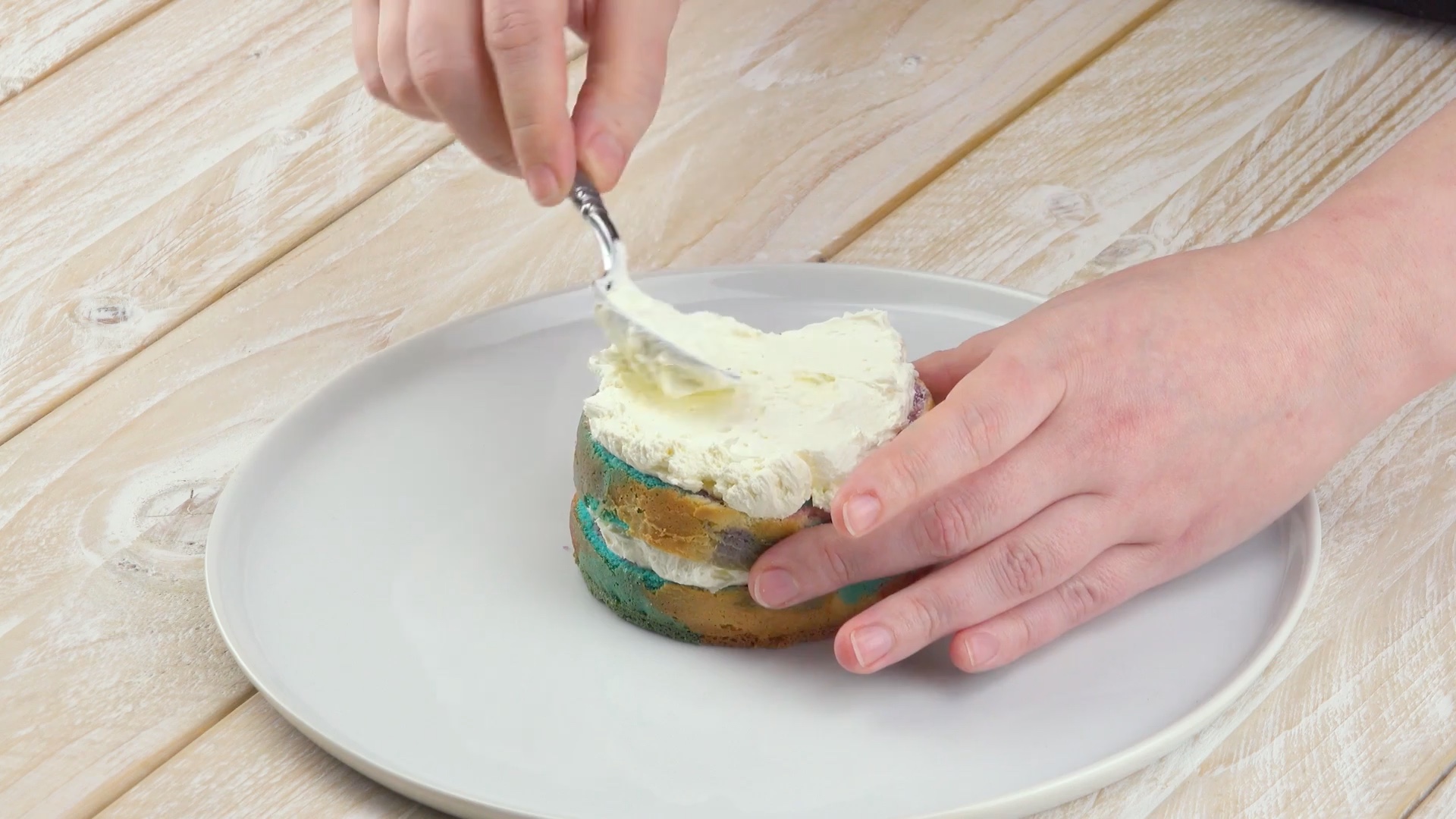 Ausgekühlter Boden wird übereinandergestapelt und mit weißer Buttercreme eingestrichen