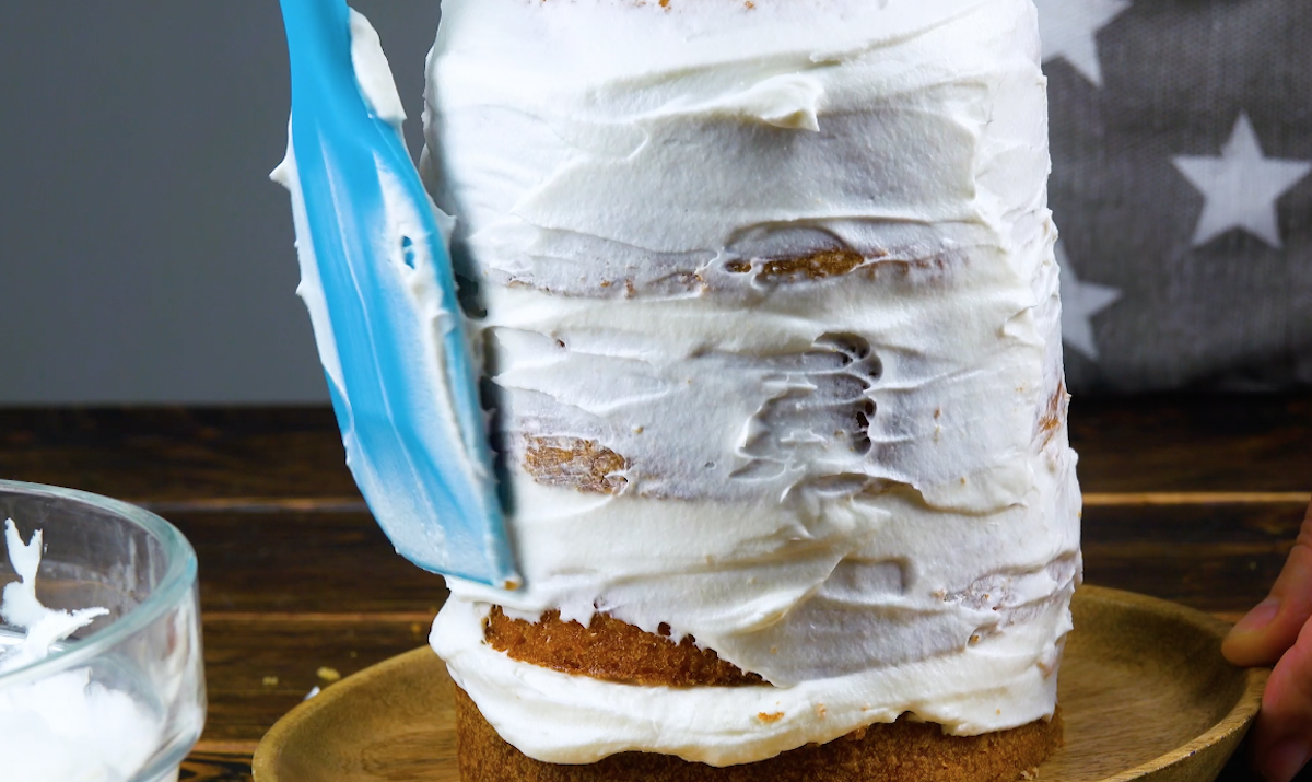 Die Kuchenböden wurden aufeinander gestapelt und dann mit der weißen Frischkäsecreme ummantelt