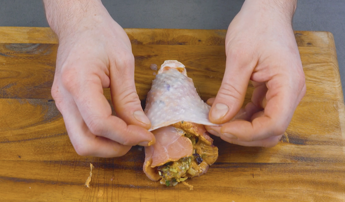 Haut wird über gefüllten Hähnchenschenkel geklappt