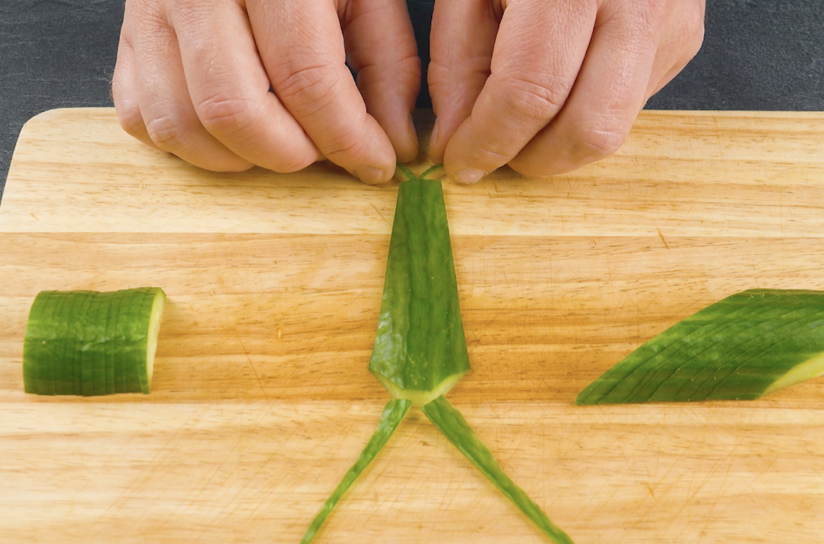 Einzelne Gurkenteile werden zu Libellenkörper geformt