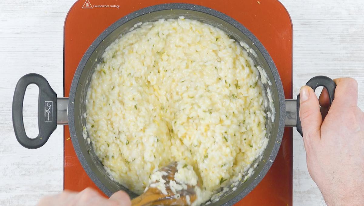 Risotto in Topf wird mit Holzlöffel umgerührt