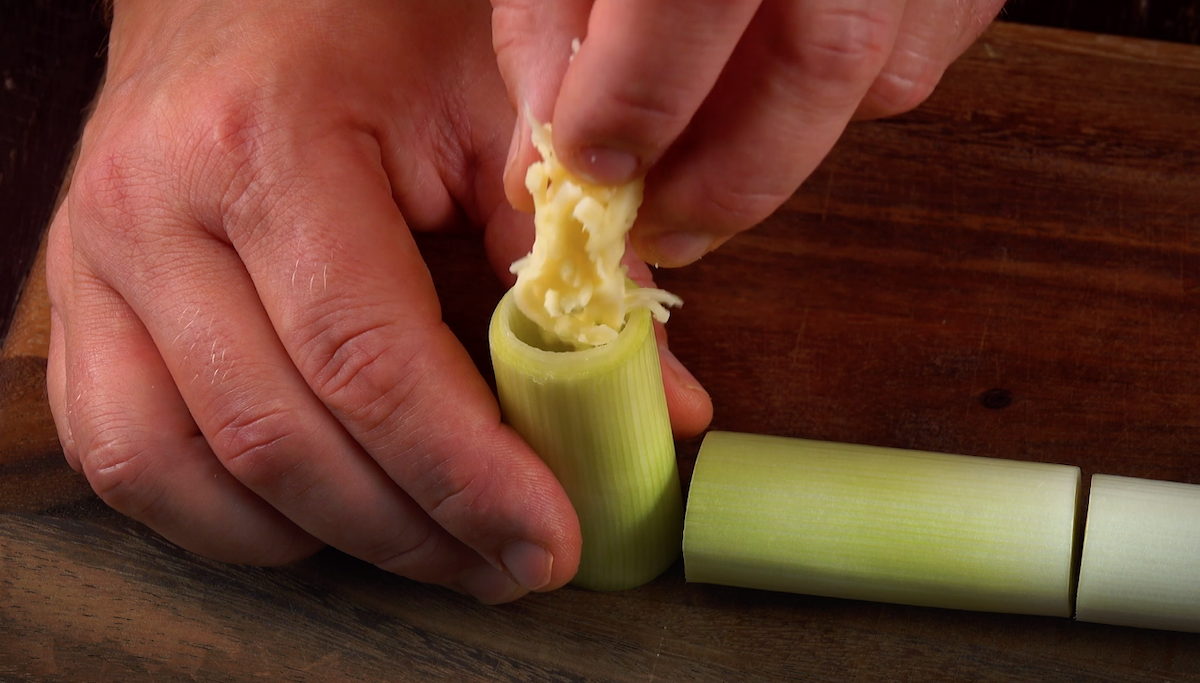 Geriebener Käse wird in eine kleine Stange Lauch gedrückt
