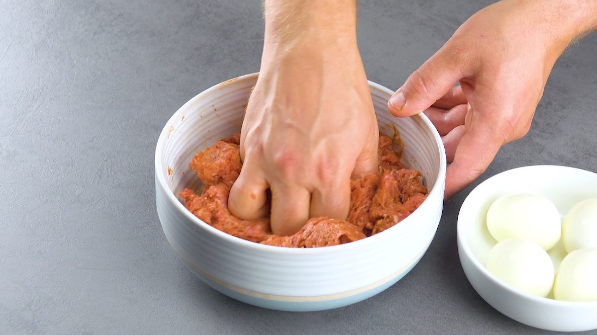 Hackfleisch wird mit Händen in Schüssel geknetet