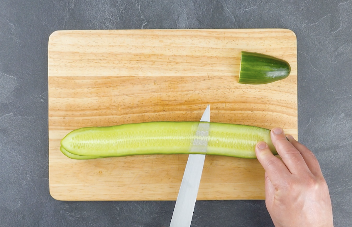 Lange, dünne Scheibe wird von halbierter Gurke abgeschnitten