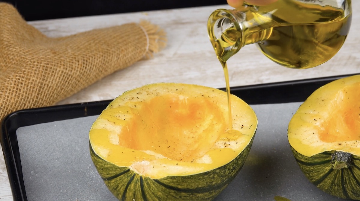 Ausgehöhlte Spaghettikürbishälften werden mit Öl beträufelt