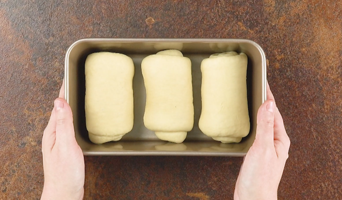 Drei zusammengerollte Hefeteigstücke in einer Kastenform