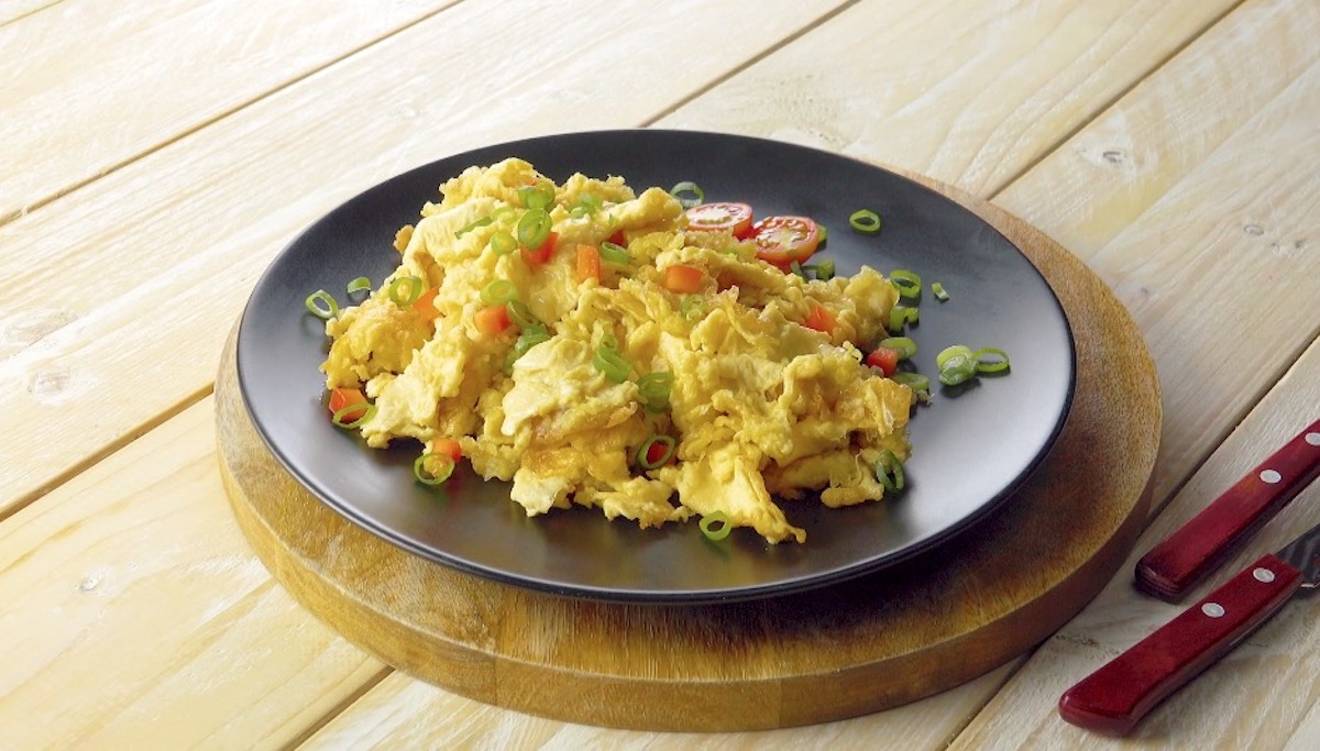 Frittiertes Ei mit Tomaten, Paprika und Schnittlauch auf Teller 