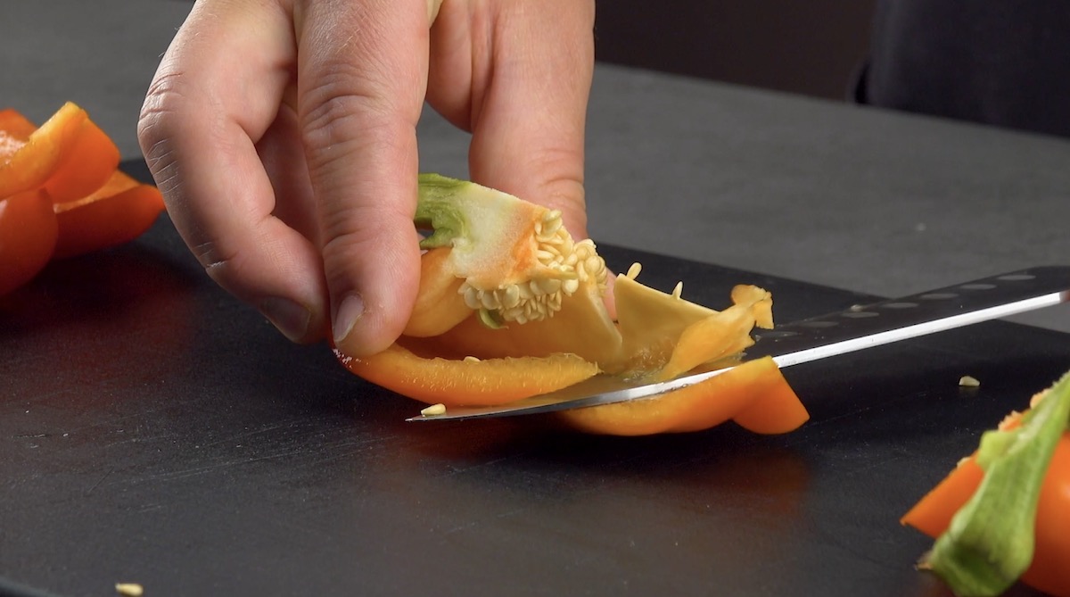 Rote Paprika wird entkernt und in Stücke geschnitten