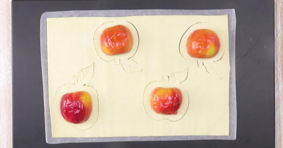 Apfelhälften werden verkehrt herum auf Blätterteig gelegt und rundherum ausgeschnitten