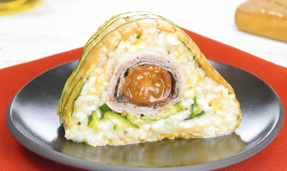 Ein Stück Zucchini-Kuchen mit Risotto und gefüllten Schinkenröllchen