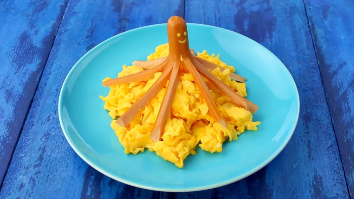 Würstchen in Krakenform auf einem Berg Rührei auf Teller