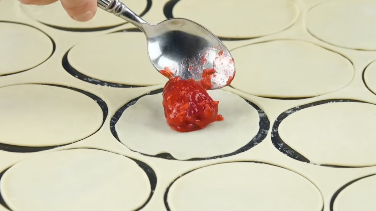 Ein Klecks Himbeeren wird mit Löffel auf Teigkreis gelegt