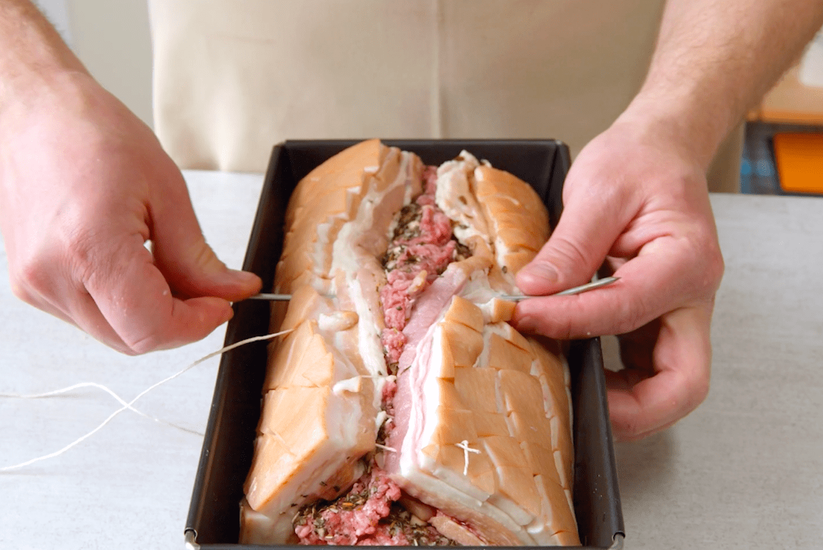 Gefüllter Schweinebauch wird zusammengenäht