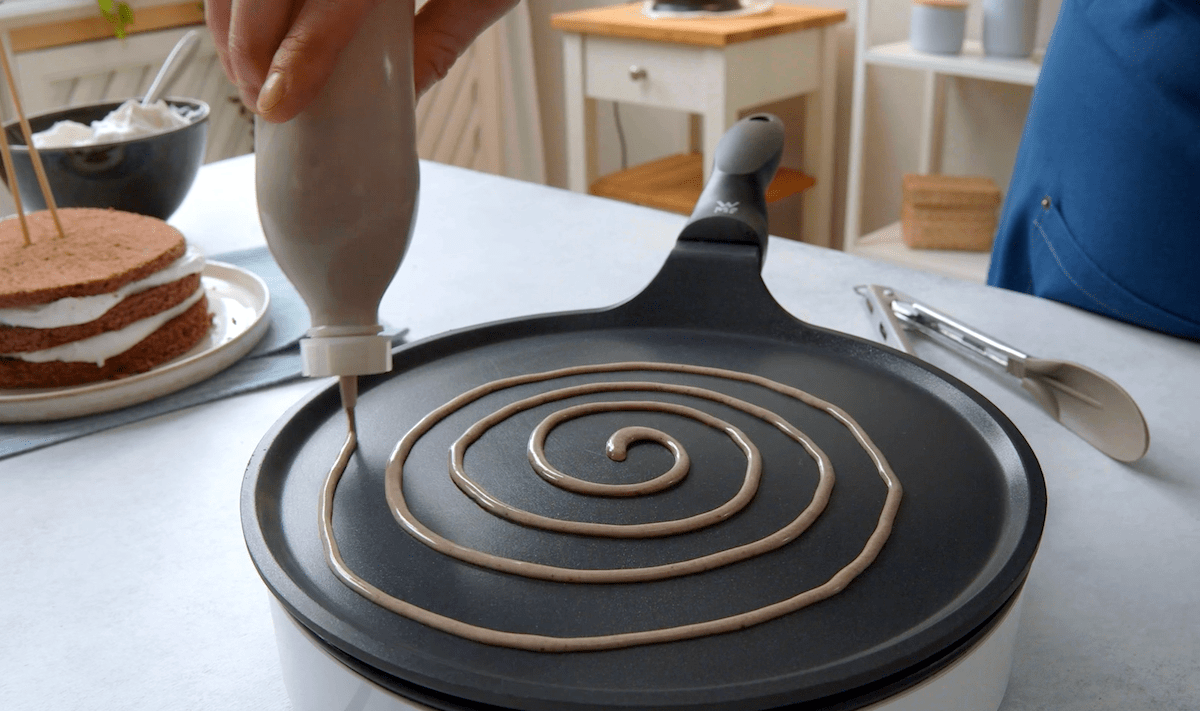 Teig wird mit einer Spritztülle spiralförmig in eine Pfanne gedrückt. So entstehen die Oreo-Nudeln.