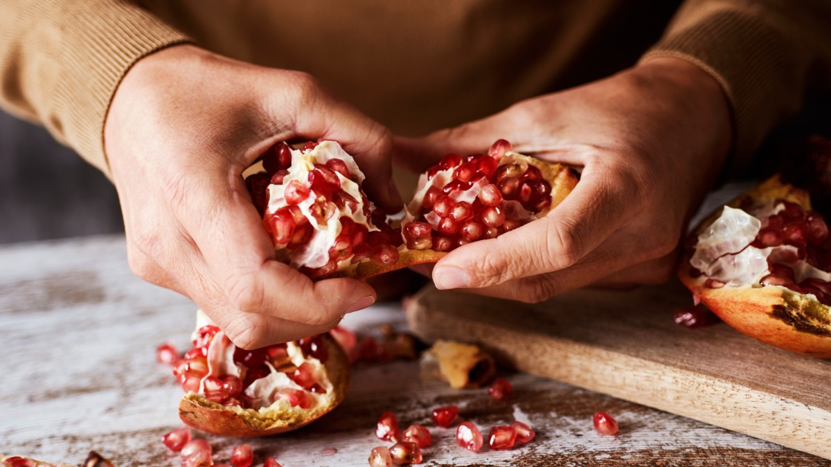 Ein Mann schÃ¤lt einen Granatapfel mit seinen HÃ¤nden