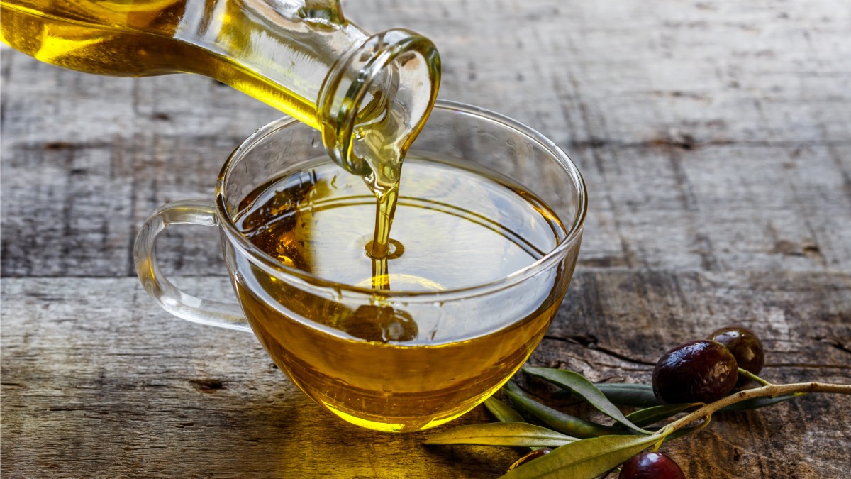 Olivenöl wird aus einer Glaskaraffe in eine Schüssel gegossen