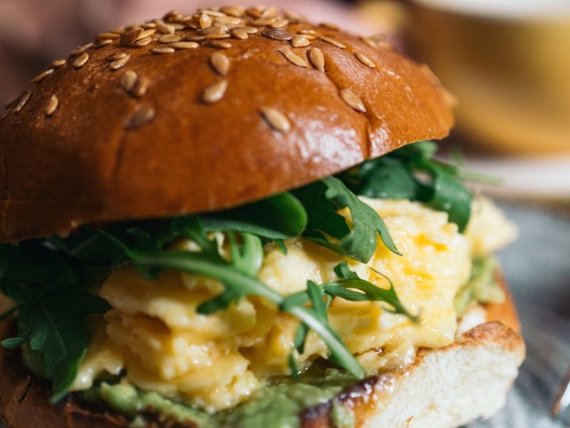 Frühstücksburger mit Rührei und Rucola, serviert auf einem Teller.