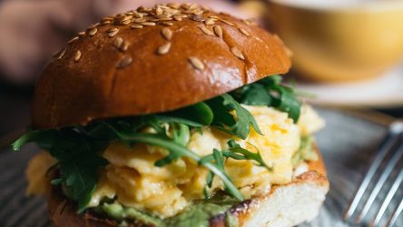 Frühstücksburger mit Rührei und Rucola, serviert auf einem Teller.