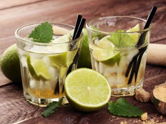 Zwei Cocktailgläser mit Ipanema stehen nebeneinander. Halbierte Limetten liegen als Dekoration davor und daneben.